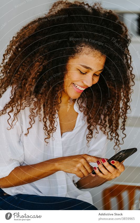 Stylish ethnic woman using smartphone at home style afro curly hair modern young female black african american mobile device gadget browsing lifestyle