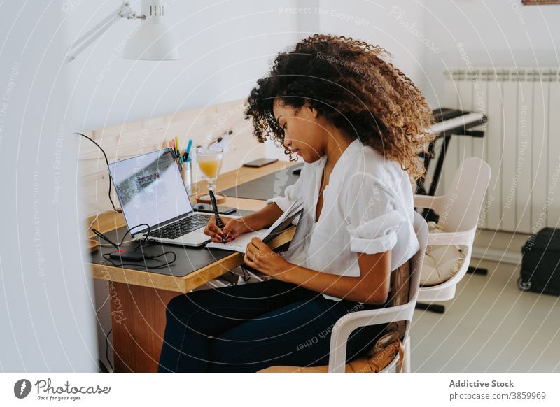 Ethnic woman working remotely from home at home freelance laptop take note write modern planner young african american black ethnic female job gadget device