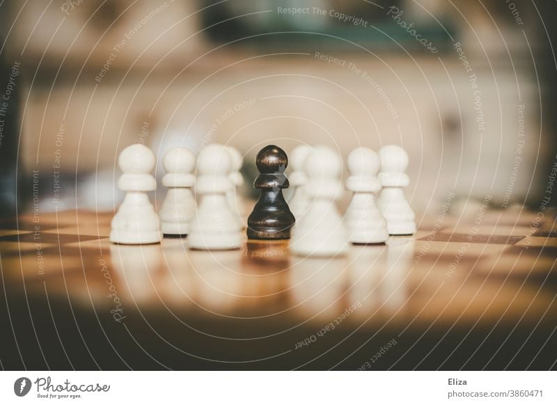 A black pawn surrounded by white pawns on a chessboard peasant Chess Chess piece Playing Chess Black White Racism Surrounded encircled differently Chessboard