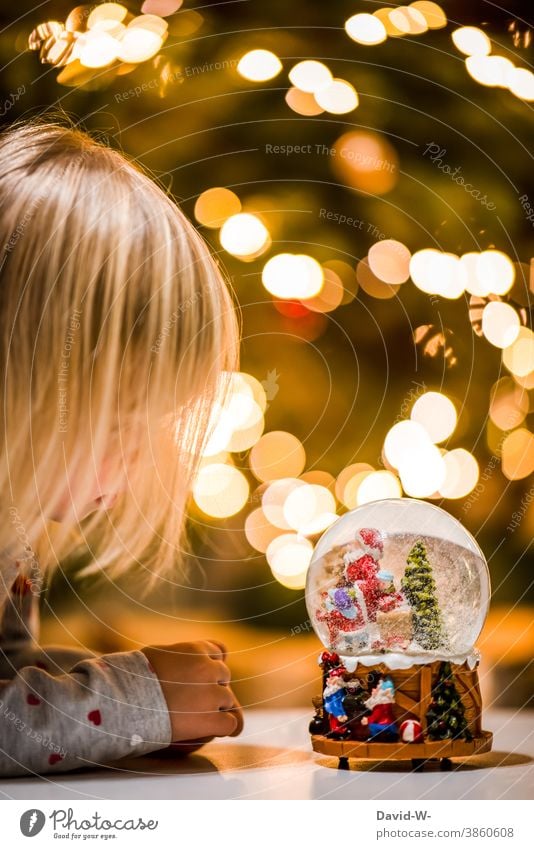 little girl looks at christmas in a snow globe Christmas & Advent Girl Snowglobe wish Desire Belief Anticipation Santa Claus Illuminate Christmas tree Joy