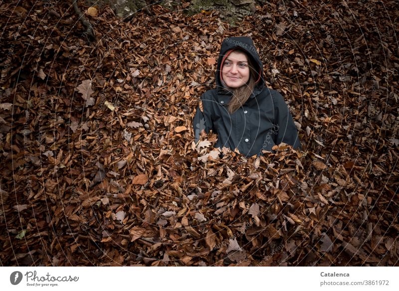 Young, smiling woman in the leaves Young woman Smiling Sit long hairs Brunette foliage Plant flora Autumn Anorak Black Brown heap of leaves
