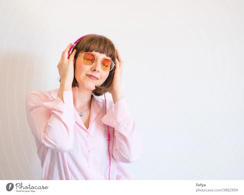 Young happy woman in pink shirt with headphones fashion sunglasses smile music listen engrossed engaged young color lifestyle using technology communication