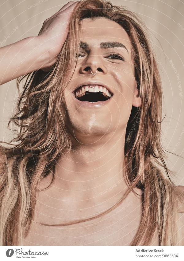 Young shirtless androgynous man laughing makeup appearance transgender happy model young male headband piercing excited queer lgbtq fashion joy positive style