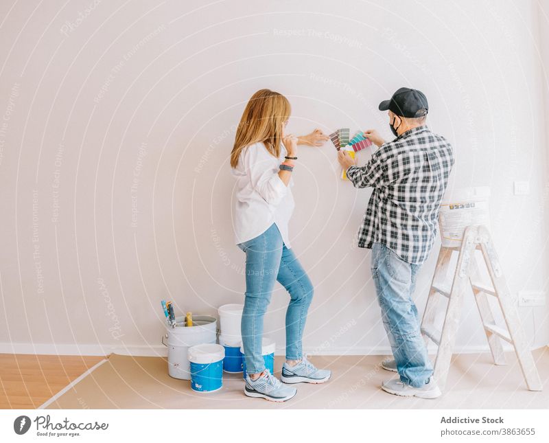 Woman and man in masks choosing colors of walls in room renovate apartment palette paper choose pick woman process work design home job worker painter flat