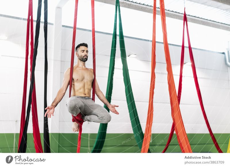 Shirtless gymnast meditating on fabric man aerial silk ribbon meditate studio hang dancer practice balance male shirtless muscular choreography perform