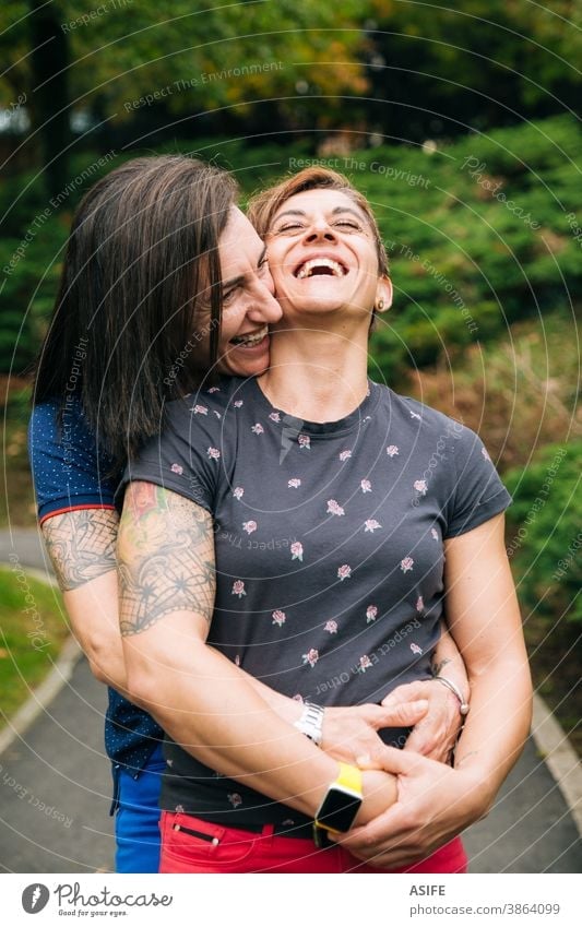 Laughing middle aged lesbian couple hugging outdoor LGBTQ gay 40 50 laughing holding embrace smile homosexual women real people candid love girlfriend family