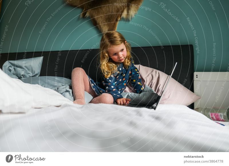 Little Caucasian Girl Using Laptop on Bed child girl caucasian laptop bed computer blond 5 years old long shot real life real person lifestyle domestic life