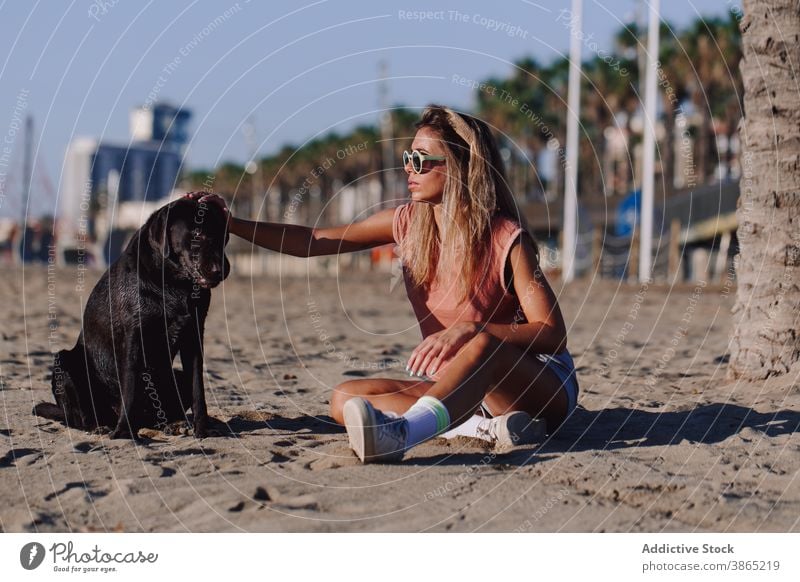 Woman with cute dog on beach woman sunset carefree stroke together seashore friendship labrador retriever female adorable black animal pet young rest nature