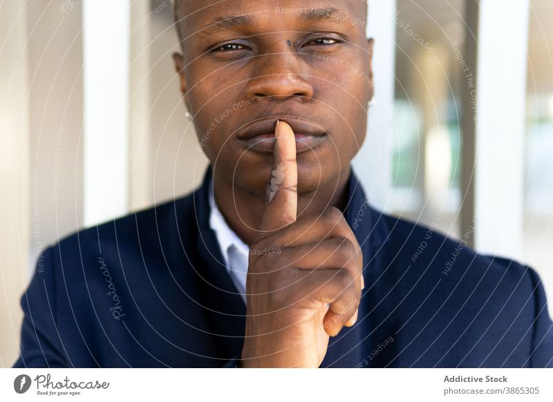 Glad black man looking at camera portrait making gesture appearance silence casual outfit piercing earring cool male ethnic african american modern confident