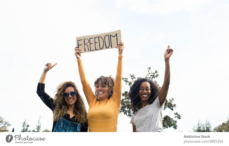 Diverse women with poster Freedom in park freedom concept inscription friend together placard unity gather multiethnic multiracial diverse black