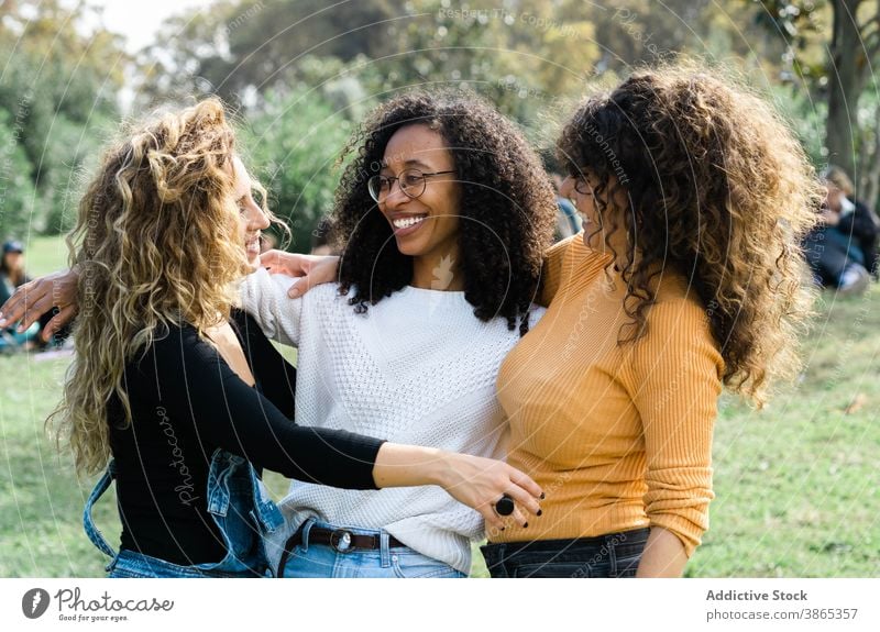 Company of women hugging in park friend cuddle friendship together cheerful group young multiracial multiethnic diverse black african american curly hair