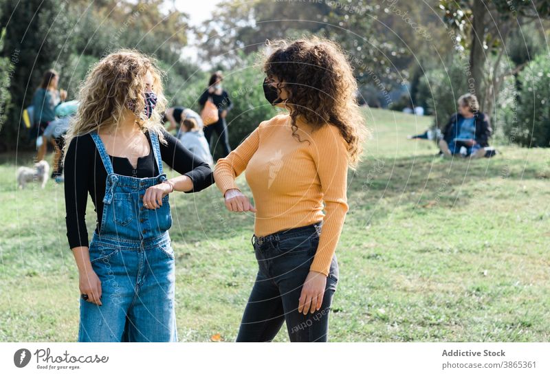 Women in masks bumping elbows in park coronavirus greeting women friend together covid 19 new normal epidemic gesture safety communicate protect friendship