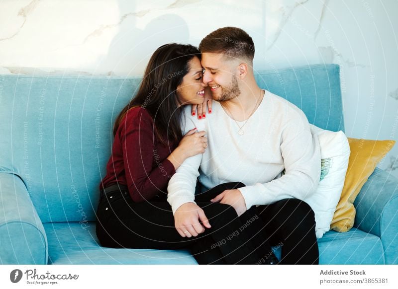Gentle couple cuddling on couch at home hug together love embrace cuddle relationship tender soft sofa cozy room carefree relax girlfriend apartment happy