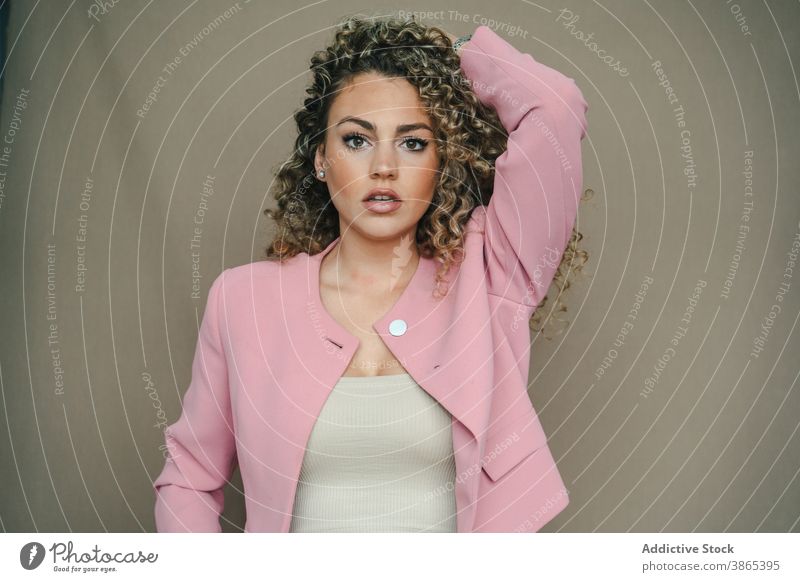 Fashionable woman in trendy outfit in studio apparel style curly hair afro hairstyle model female slim individuality contemporary cool cloth elegant jacket suit