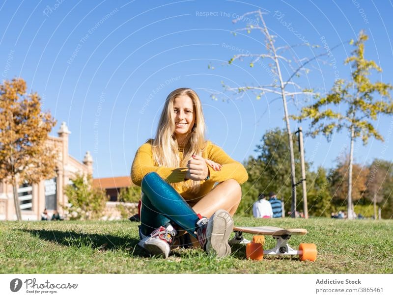 Delighted female skater with bionic prosthesis park woman leg longboard artificial limb relax summer city carefree amputee urban grass lawn disable street town