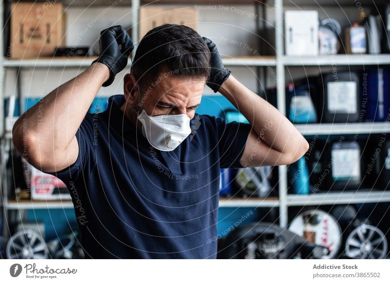 Worker putting white face mask man worker put on glove garage prepare latex uniform busy male staff job employee professional occupation service industry