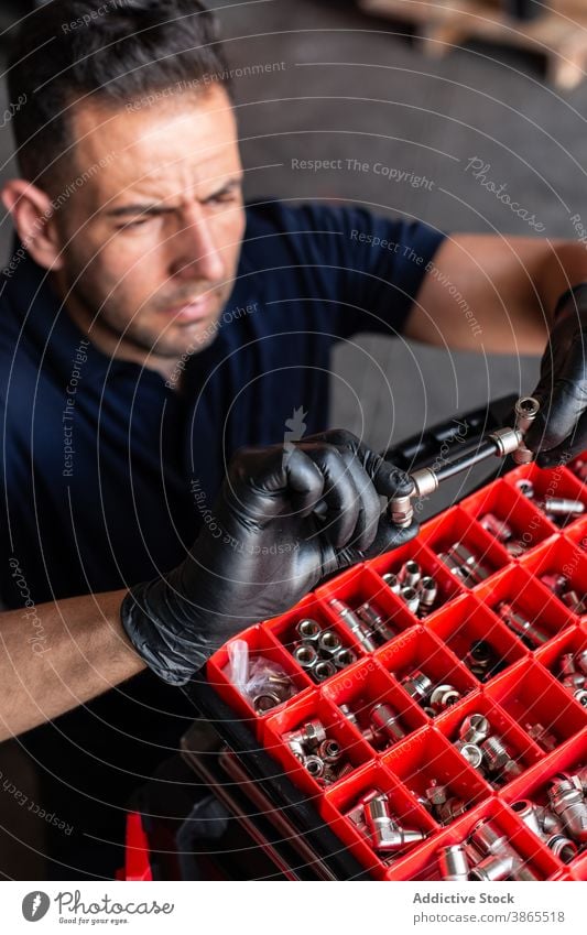 Male technician examining tool in garage man mechanic examine box work glove modern professional male adult workplace latex instrument workshop job occupation