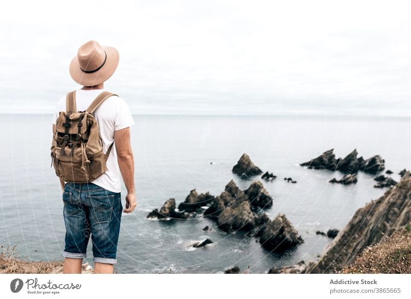 Man standing on hill and enjoying seascape traveler observe viewpoint man explore wanderlust adventure wonderful male scenery rocky mountain cloudy sky nature