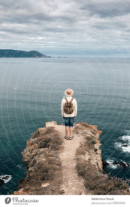 Man standing on hill and enjoying seascape traveler observe viewpoint man explore wanderlust adventure wonderful male scenery rocky mountain cloudy sky nature
