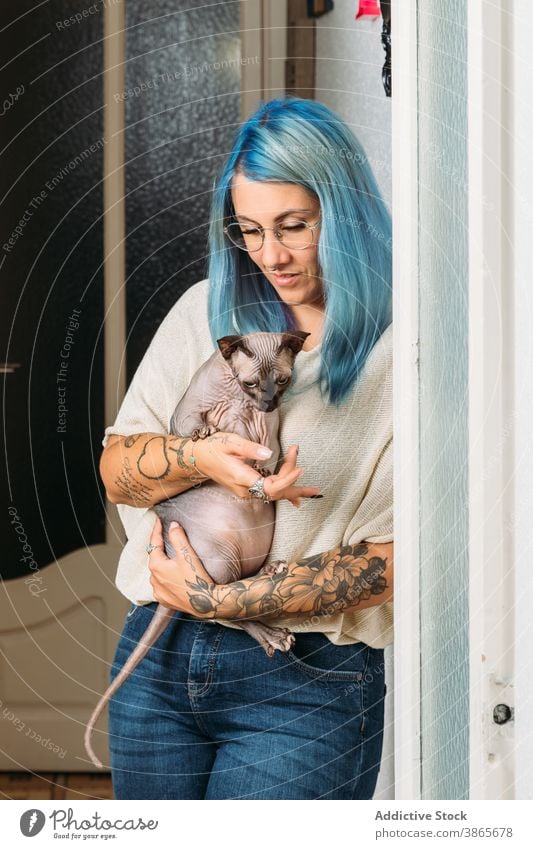 Young woman hugging cat in hallway corridor home informal lean wall cozy rest owner female young subculture feline alternative sphynx hairless pet domestic