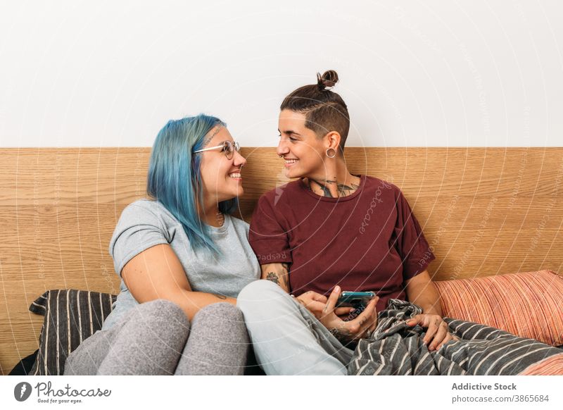 Happy lesbian couple using smartphone women bed smile home together cozy girlfriend gadget device rest happy social media bedroom browsing cheerful share lgbt
