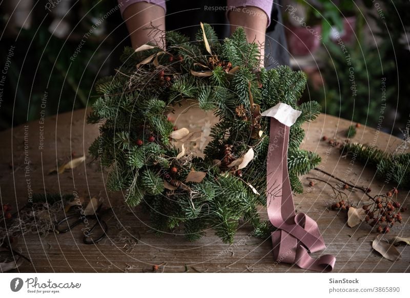 Woman making Christmas wreath of spruce, step by step. Concept of florist's work before the Christmas holidays. ribbon hand woman hands wooden table handicraft