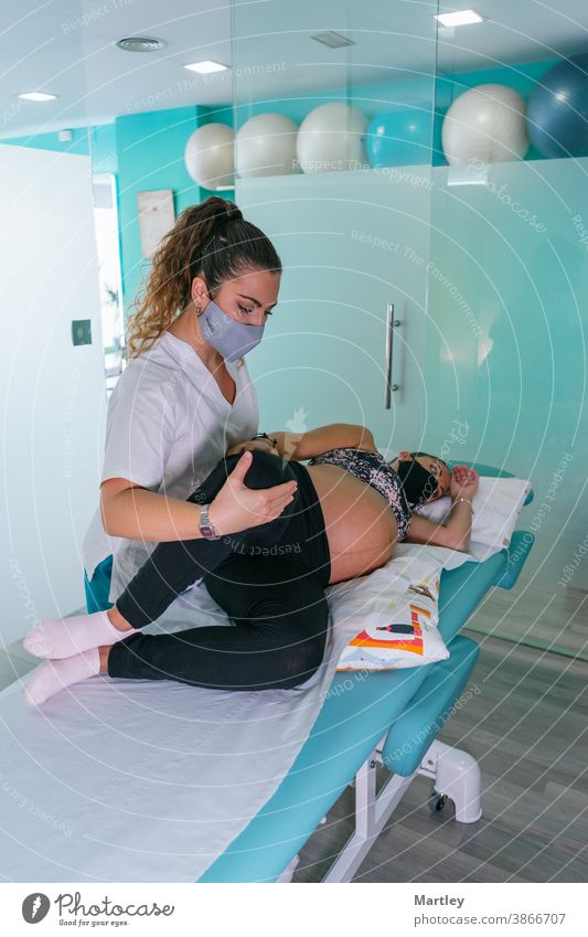 Female therapist stretching leg of pregnant during physiotherapy session in contemporary clinic pregnancy prenatal physiotherapist rehabilitation massage woman