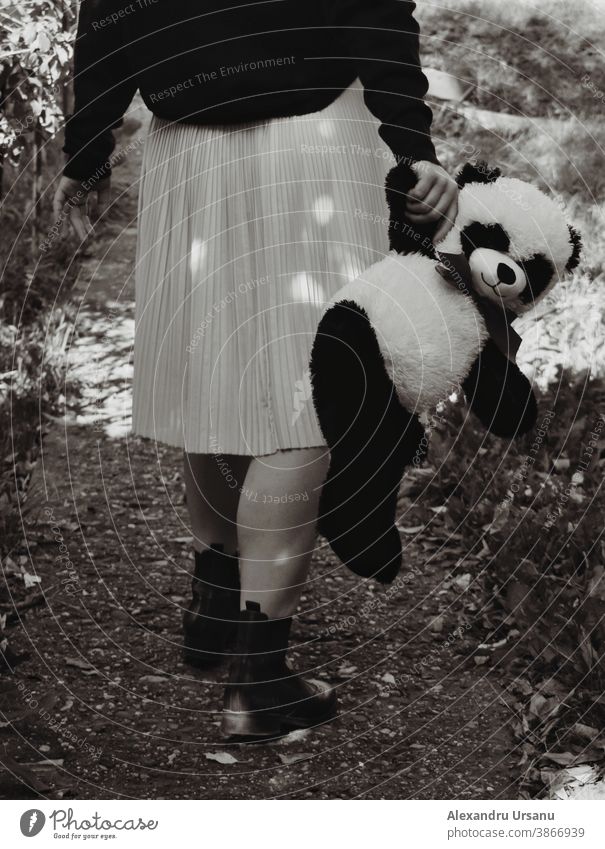 A girl is walking with a bear in her hands. Girl Legs Walking Bear toy childhood sad