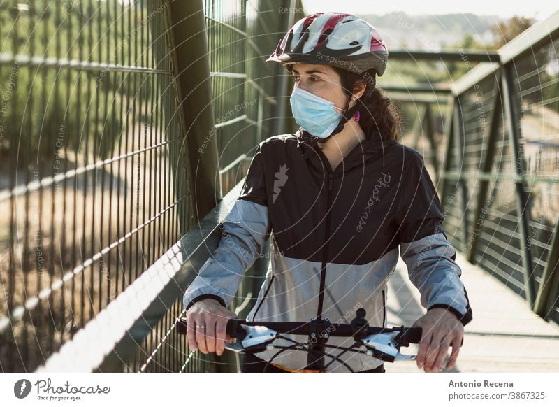 Biker with facemask training sport in pandemic time woman women covid-19 corona virus coronaviorus face mask bycicle helmet outdoors day dylight lifestyles