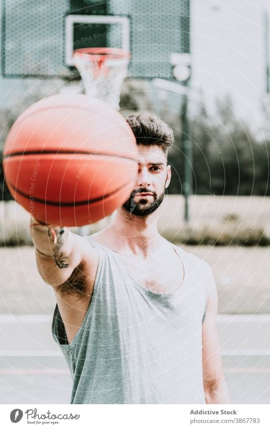 Young man with basketball ball on sports ground confident player game streetball beard young serious training playground athlete activity lifestyle sportsman