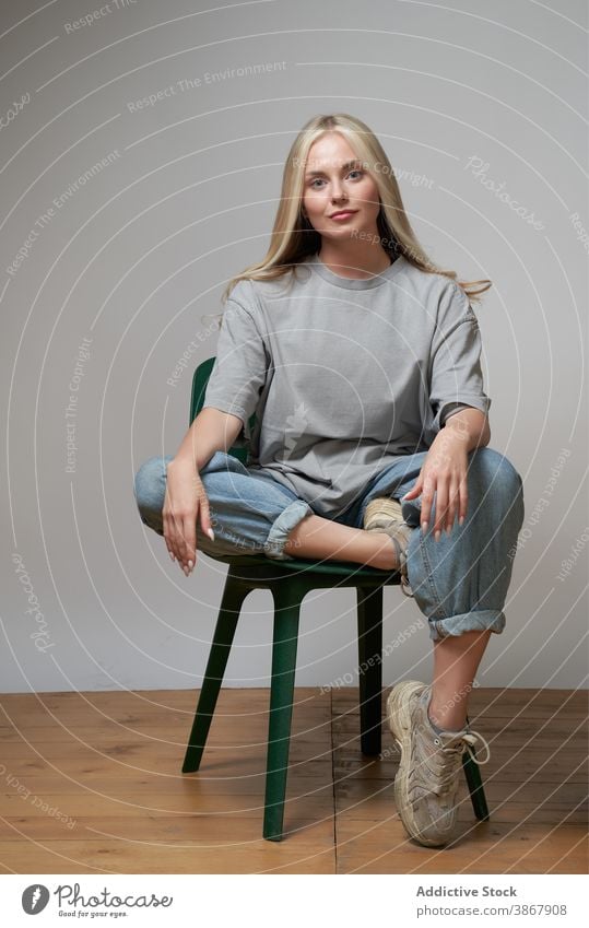 Woman in street style wear in studio cool woman independent young trendy outfit modern confident female model contemporary individuality generation sit chair