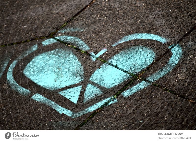 The blue heart. The cold heart. The heart of stone. The cleft heart. The heart of ice. A graffiti heart in blue and black sprayed on grey concrete slabs. Heart