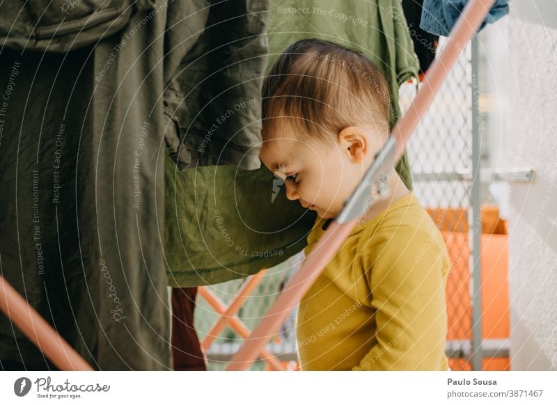 Toddler playing with clothes on the clothesline 0-09 years Lifestyle affectionate at home authentic autumn caring casual caucasian child color curiosity day