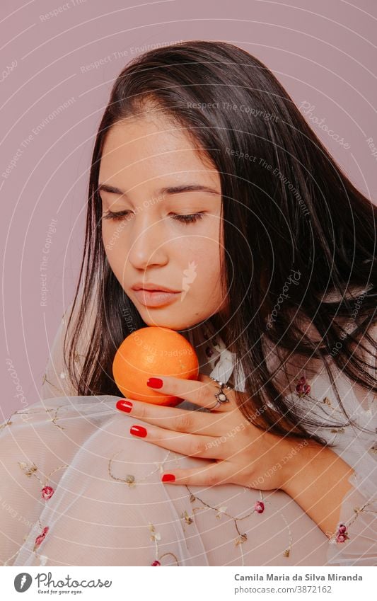 Model holding an orange. Studio shot with pink background. beautiful beauty care citrus closeup cosmetics face fashion fresh fruit girl glamour hair hairstyle