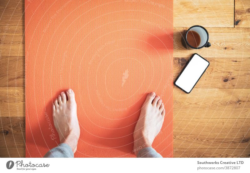 Man standing on yoga mat with coffee and mobile phone. connection technology call cellphone smart barefoot smart phone touchscreen device communication