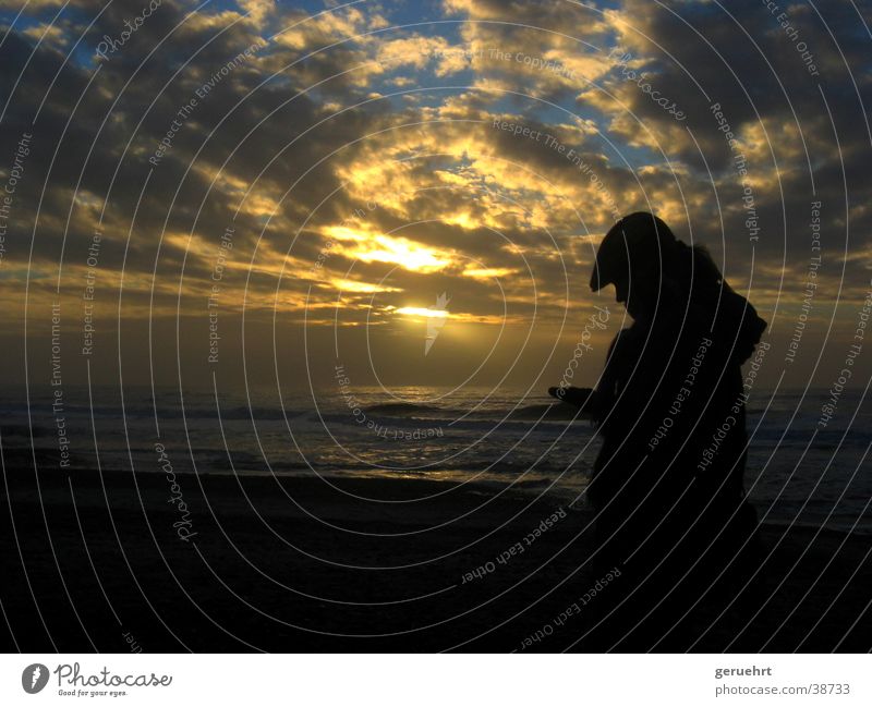 woman against light Waves Coast Beach Sunset Twilight Cloud formation Reflection Back-light Silhouette Woman Cap Hooded (clothing) Looking Appraise Think Touch