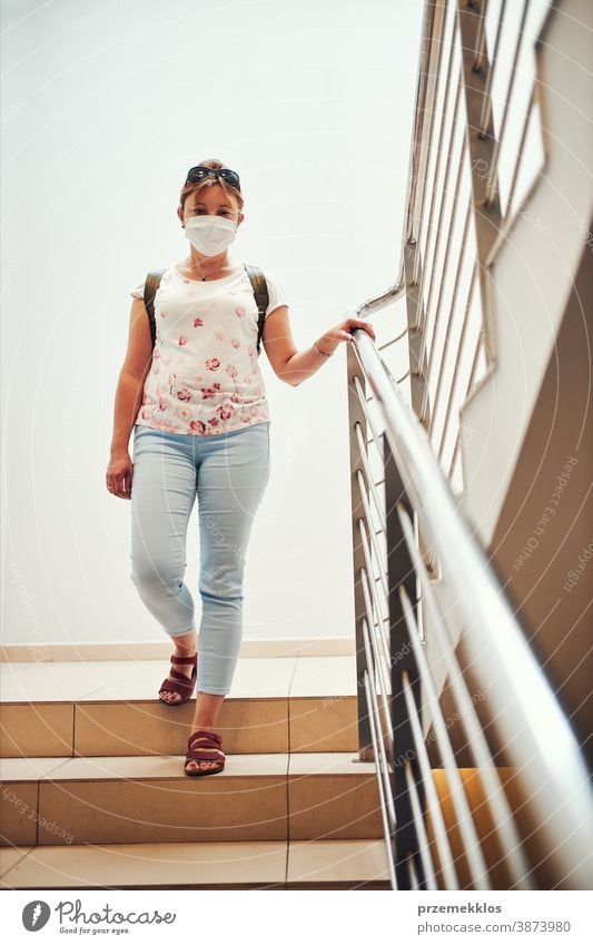 Woman going downstairs wearing face mask to cover mouth and nose during pandemic coronavirus outbreak woman pharmacy covid-19 female care indoor person protect
