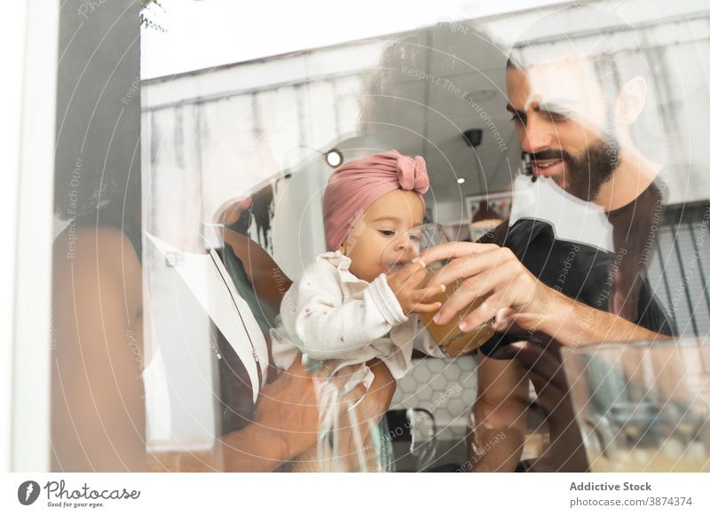 Multiethnic family together in cafe baby drink help care couple juice cute multiethnic multiracial diverse black african american mother father adorable sweet