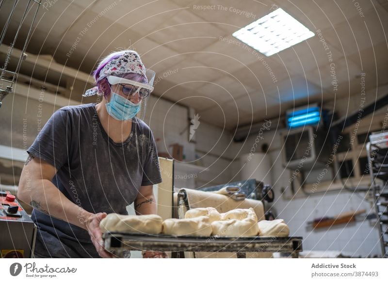 Baker preparing dough for baking bakery bread woman prepare uncooked shape round mask female shield table kitchen work culinary raw bakehouse lady covid