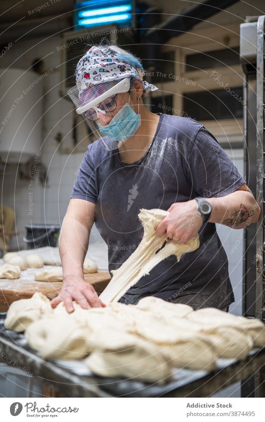 Baker preparing dough for baking bakery bread woman prepare uncooked shape round mask female shield table kitchen work culinary raw bakehouse lady covid