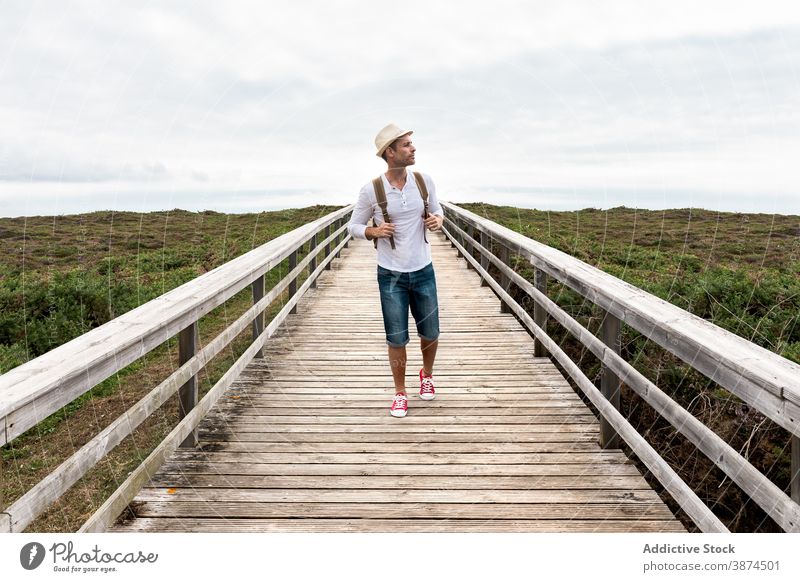 Male backpacker walking on wooden boardwalk traveler walkway man active nature explore adventure hike path journey vacation lifestyle activity summer holiday