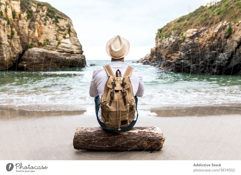 Traveler with backpack resting on seashore traveler coast man backpacker beach rock ocean relax male nature adventure tourism water lifestyle freedom recreation