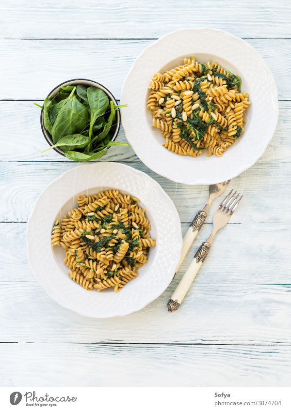 Whole grain pasta with spinach and pine nuts food plate table wood dish vegan vegetarian leaves italian baby meal rustic organic green gourmet cooking fusilli