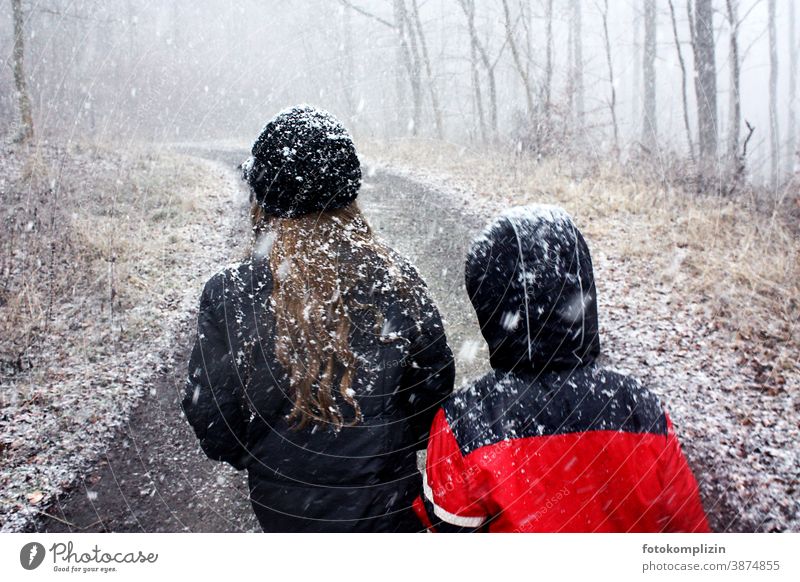 two children on a forest path while it is snowing Snowfall Snowflake Winter be a child onset of winter snowed over Infancy snowflakes Snowscape snowy