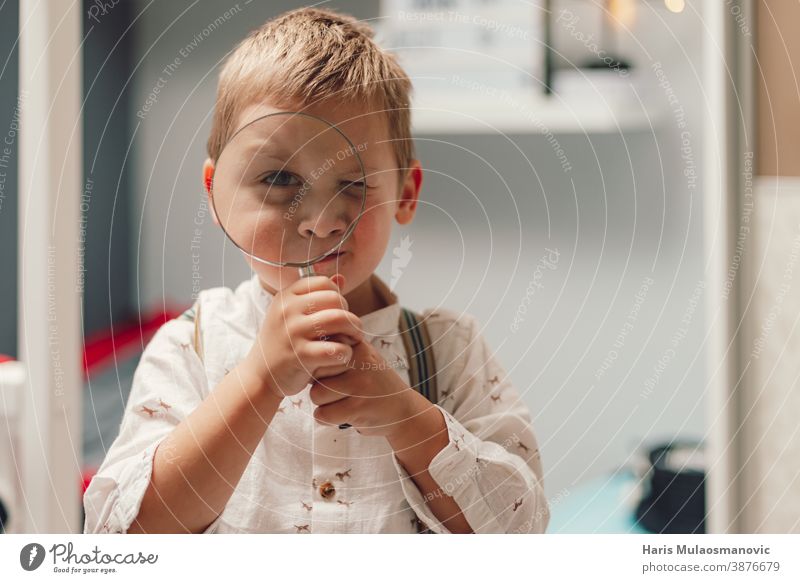 Cute little boy holding a magnifying glass beautiful care caucasian child childhood concept curiosity curious curious boy cute education face find finding a job