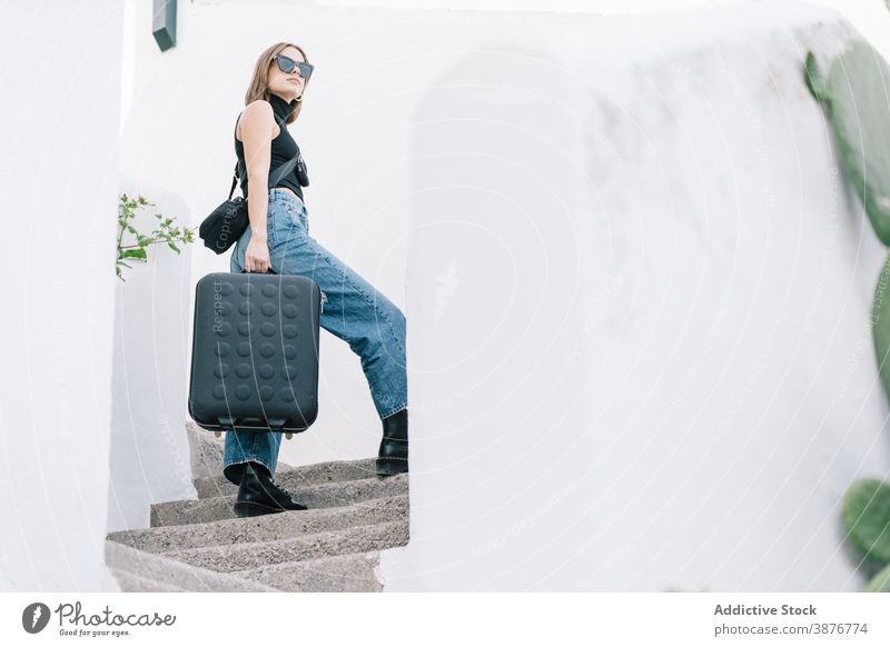 Female traveler with suitcase on stairs in city summer vacation tourist woman urban summertime female sunglasses luggage upstairs walk journey trip weekend