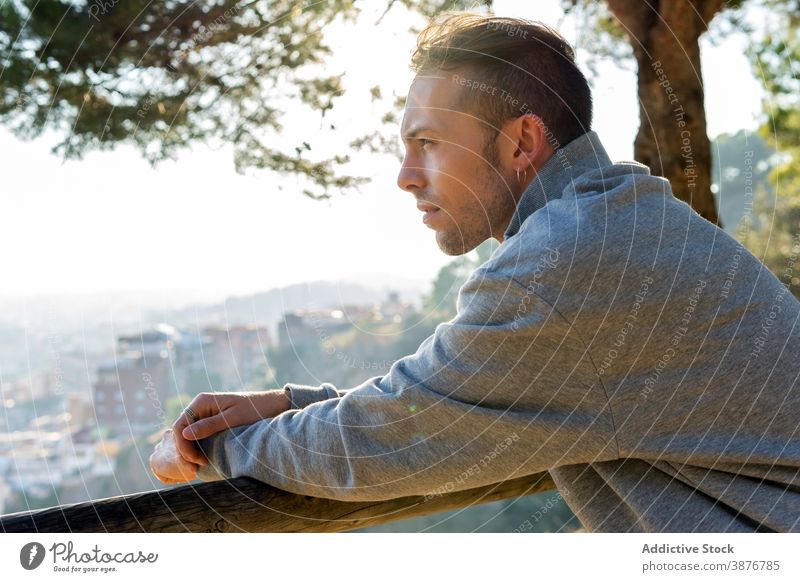 Thoughtful man resting on hill near city thoughtful pensive hipster contemplate dream think nature casual calm relax young male lifestyle guy urban dreamy