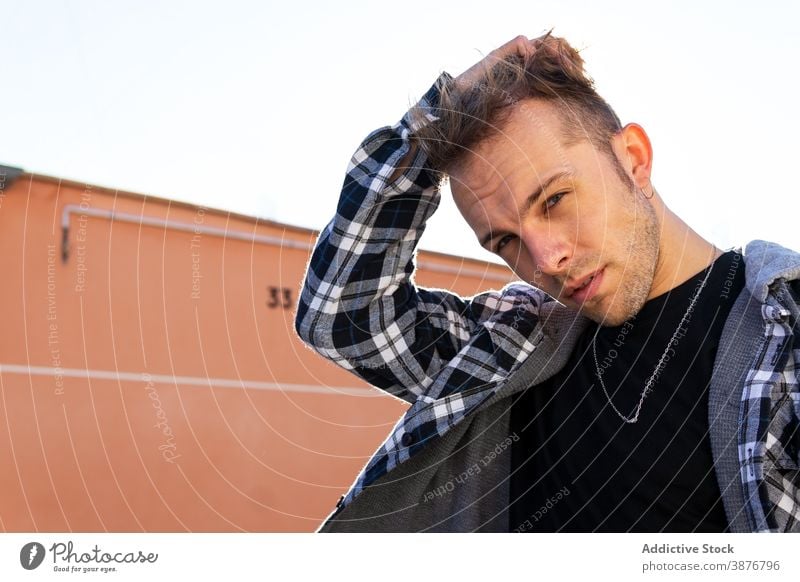 Young man in checkered shirt looking at camera hipster confident trendy portrait modern style young casual male optimist cool content urban joy handsome glad
