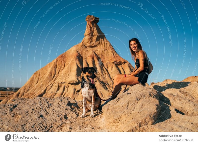 Smiling woman with dog in rocky desert vacation travel together adventure sunny arid female bardenas reales spain summer canine sit happy cheerful pet enjoy
