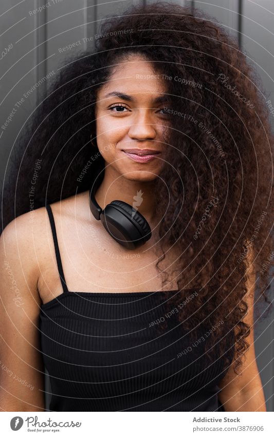 Charming ethnic woman with headphones on street curly hair afro hairstyle charming smile natural beauty female black african american city trendy rest joy